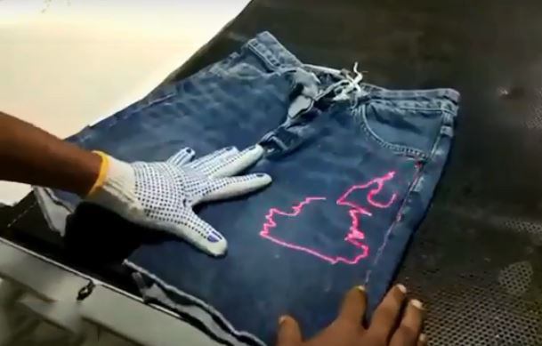 Công nhân đang gia công quần jeans bằng máy bắn Laser