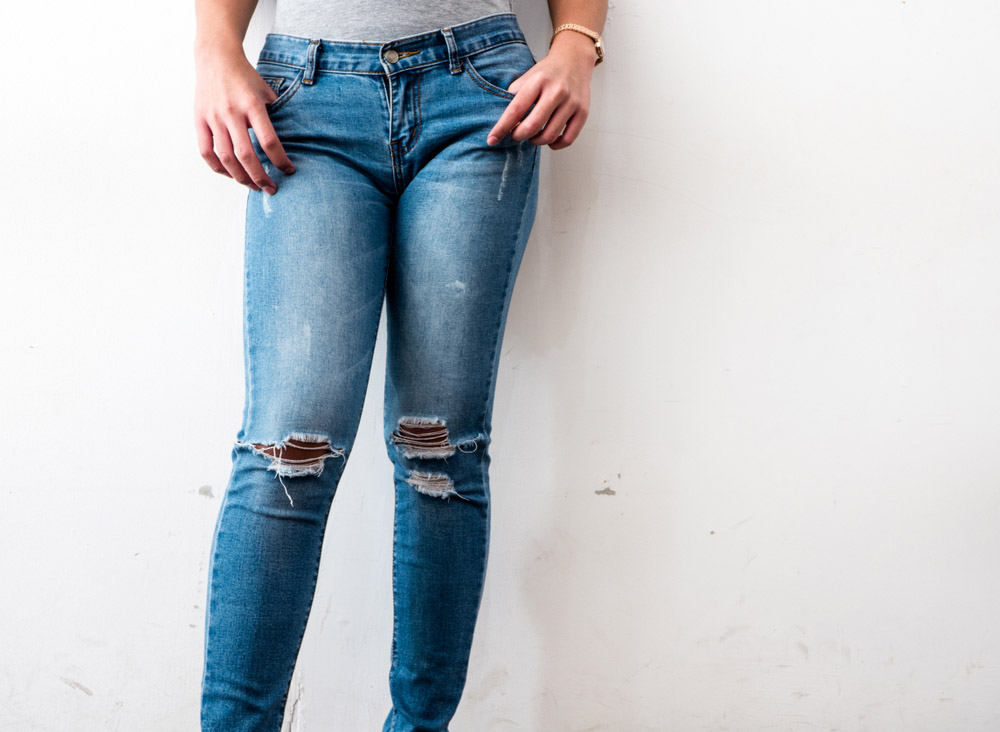 Vết rách dạng xé kết hợp với lổ thủng vùng gối dành trên 1 chiếc quần Jeans nữ