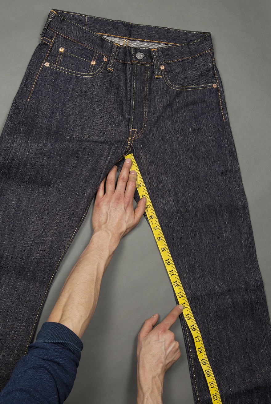 Một chiếc quần jeans đang được người thợ đo độ dài đường may inseam